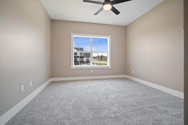 carpeted spare room featuring ceiling fan and baseboards