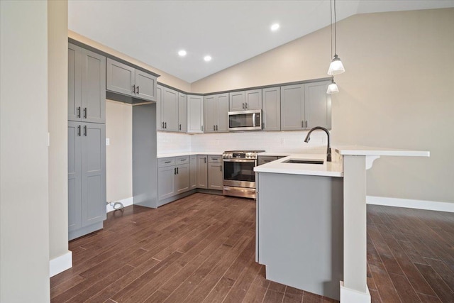 kitchen with stainless steel appliances, a peninsula, a sink, light countertops, and decorative light fixtures