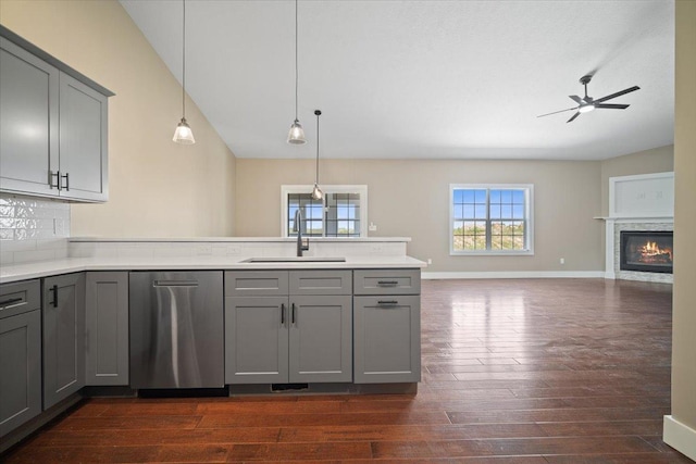 kitchen with a sink, open floor plan, light countertops, stainless steel dishwasher, and gray cabinets