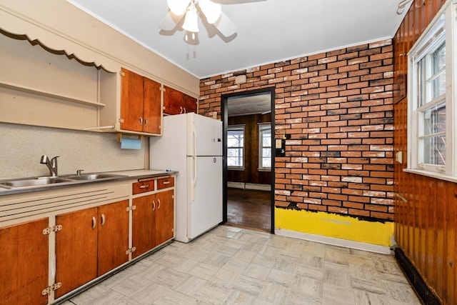 kitchen featuring ceiling fan, sink, brick wall, and white refrigerator