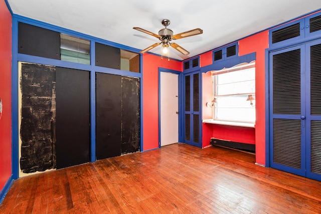 unfurnished bedroom featuring hardwood / wood-style floors, ceiling fan, and two closets