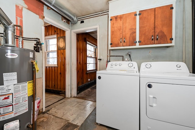 laundry room featuring cabinets, gas water heater, wood walls, and washing machine and clothes dryer