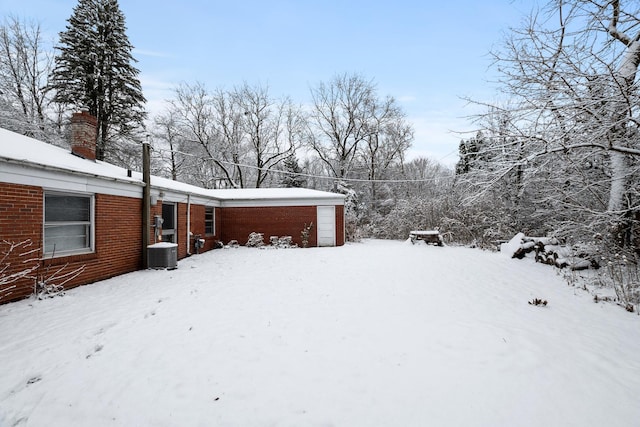 snowy yard with a garage and central AC