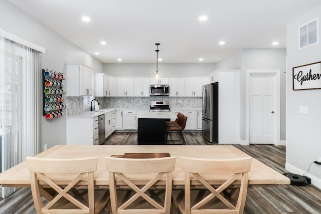 kitchen featuring white cabinets, sink, decorative light fixtures, a kitchen island, and stainless steel appliances