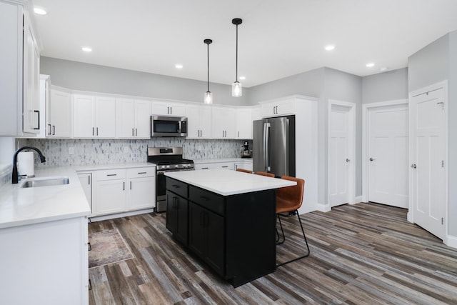 kitchen with dark hardwood / wood-style floors, a kitchen island, sink, and stainless steel appliances