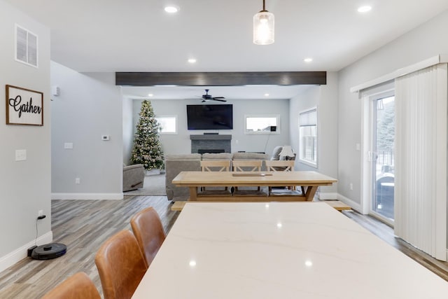 kitchen featuring pendant lighting, a kitchen bar, ceiling fan, light wood-type flooring, and light stone counters