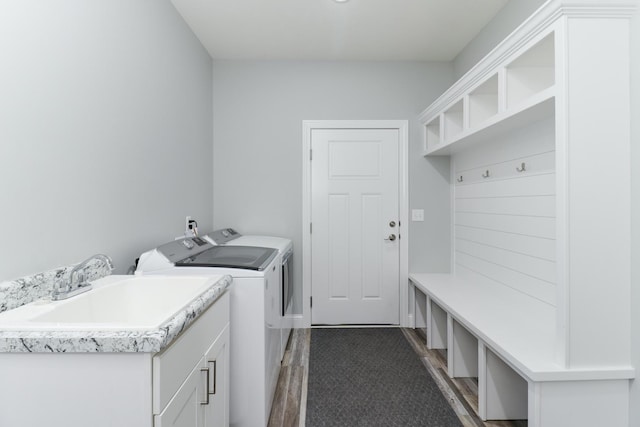 washroom featuring washing machine and dryer, sink, cabinets, and dark hardwood / wood-style floors