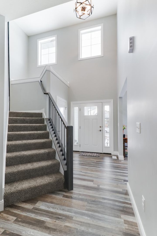 entryway with wood-type flooring, a notable chandelier, and a high ceiling