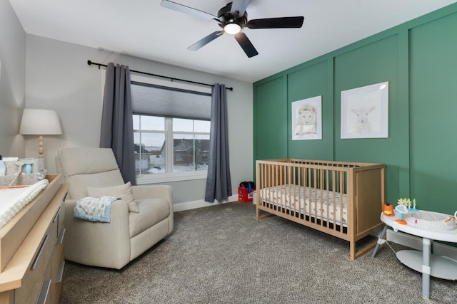 carpeted bedroom featuring ceiling fan and a crib