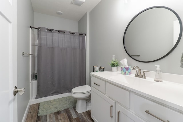 full bathroom with hardwood / wood-style flooring, vanity, shower / bath combination with curtain, and toilet