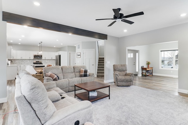 living room featuring beam ceiling, light wood-type flooring, and ceiling fan