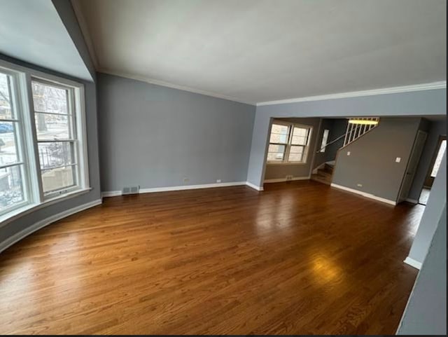 unfurnished living room featuring ornamental molding, stairway, and wood finished floors