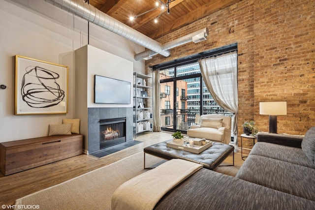 living room featuring brick wall, a tile fireplace, wooden ceiling, beamed ceiling, and a high ceiling