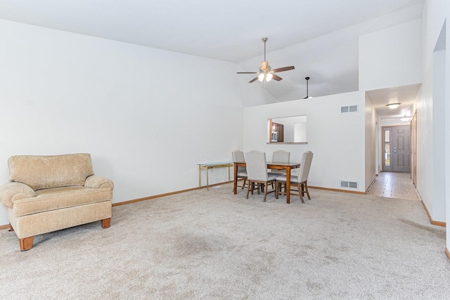 dining room with ceiling fan, light carpet, and high vaulted ceiling