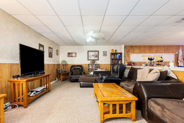 carpeted living room featuring a paneled ceiling and wood walls