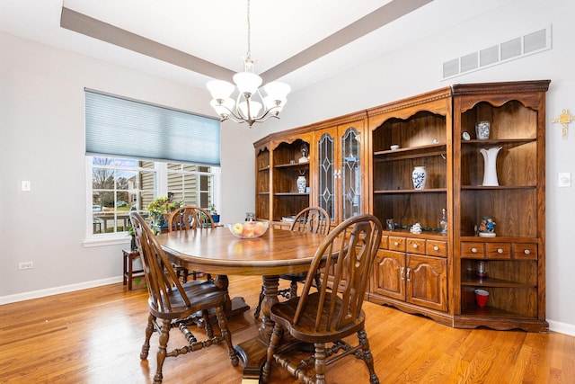 dining space with light hardwood / wood-style floors and an inviting chandelier