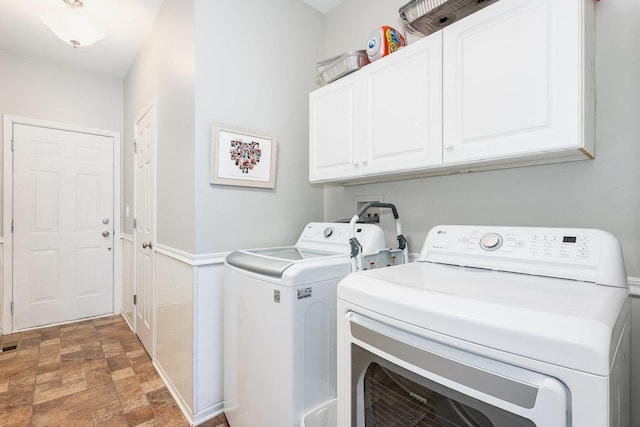 clothes washing area featuring washing machine and dryer and cabinets