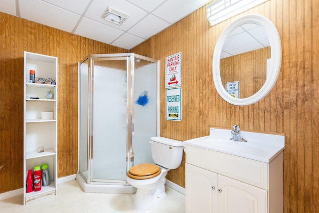 bathroom featuring wood walls, toilet, a paneled ceiling, a shower with door, and vanity