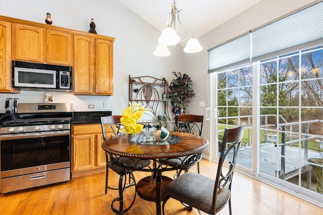 kitchen with hanging light fixtures, stainless steel range with gas cooktop, a chandelier, lofted ceiling, and light hardwood / wood-style floors