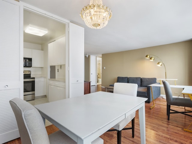 dining area with an inviting chandelier and light hardwood / wood-style flooring