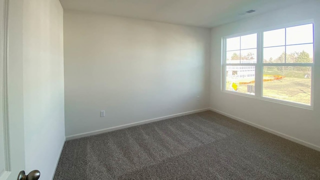 empty room with dark carpet and a wealth of natural light