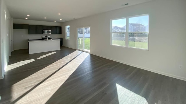 unfurnished living room with dark hardwood / wood-style floors and a healthy amount of sunlight