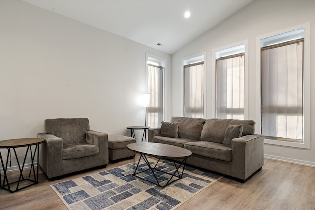 living room featuring light wood-type flooring, lofted ceiling, and a wealth of natural light