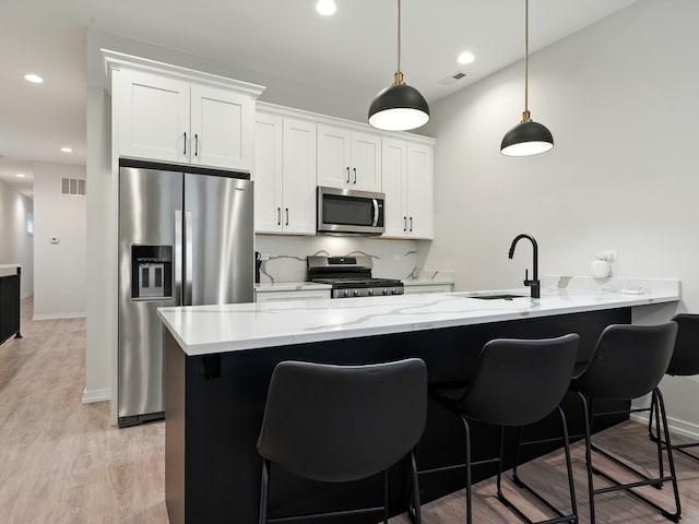 kitchen featuring backsplash, sink, appliances with stainless steel finishes, decorative light fixtures, and white cabinetry