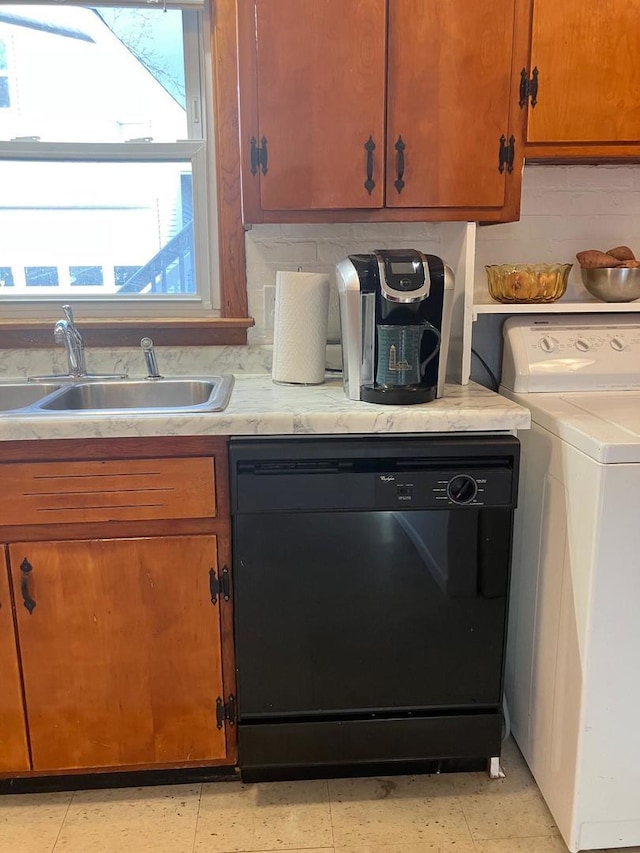 kitchen featuring backsplash, sink, black dishwasher, and washer / clothes dryer