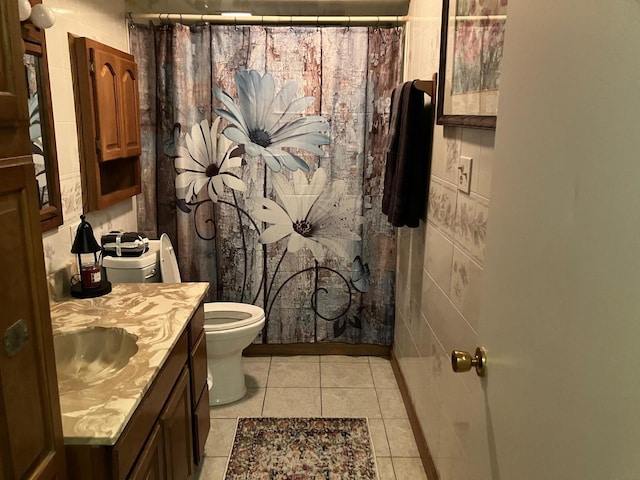 bathroom featuring vanity, tile patterned flooring, a shower with shower curtain, toilet, and tile walls