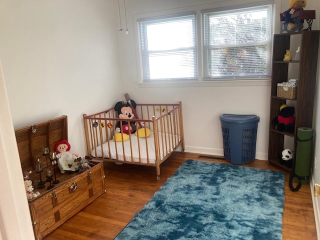 bedroom with wood-type flooring and a nursery area