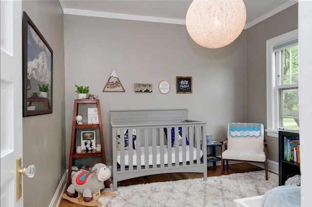 bedroom with wood-type flooring, a nursery area, and ornamental molding