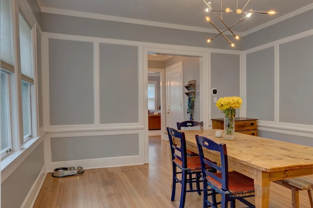 dining area featuring light hardwood / wood-style flooring, an inviting chandelier, and crown molding