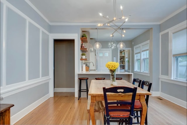 dining room featuring crown molding, light hardwood / wood-style flooring, an inviting chandelier, and sink