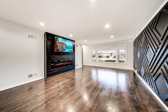 unfurnished living room with hardwood / wood-style floors, a large fireplace, and ornamental molding