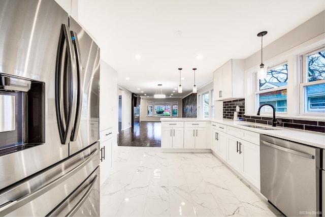 kitchen with sink, stainless steel appliances, kitchen peninsula, pendant lighting, and white cabinets