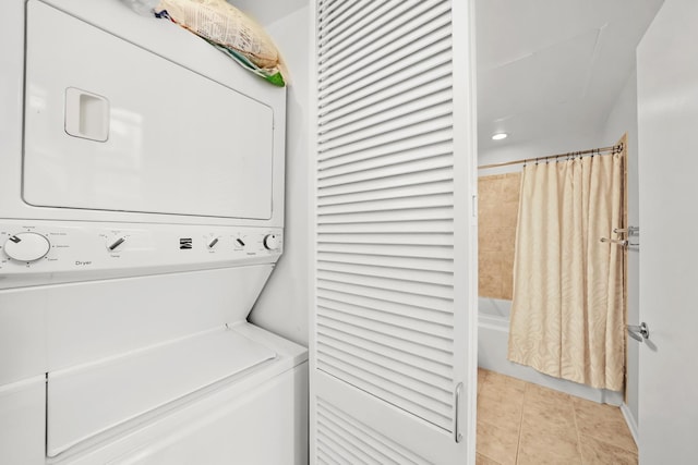 laundry area with stacked washer and clothes dryer and light tile patterned flooring