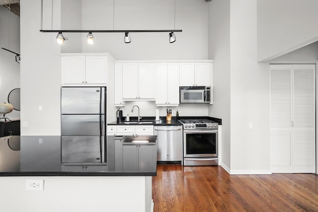 kitchen with sink, stainless steel appliances, dark hardwood / wood-style flooring, kitchen peninsula, and white cabinets