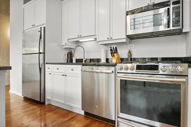 kitchen with white cabinets, dark hardwood / wood-style flooring, and stainless steel appliances