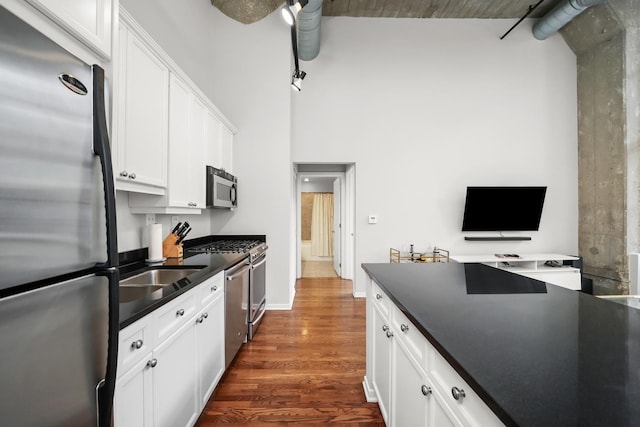 kitchen with appliances with stainless steel finishes, ceiling fan, dark wood-type flooring, sink, and white cabinetry