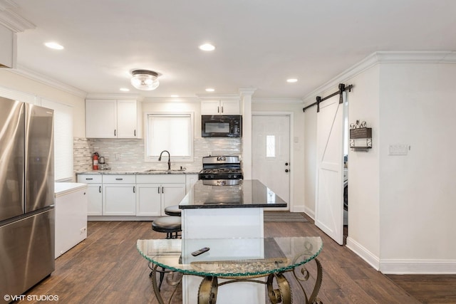 kitchen with white cabinets, a barn door, dark wood-type flooring, and appliances with stainless steel finishes