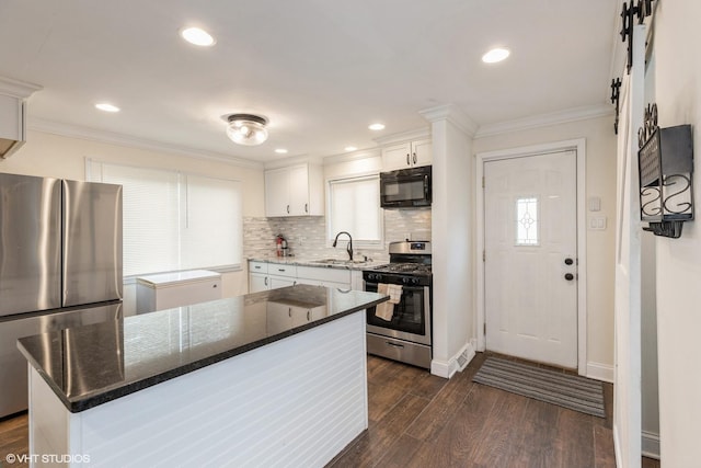 kitchen with white cabinetry, sink, dark wood-type flooring, a kitchen island, and appliances with stainless steel finishes