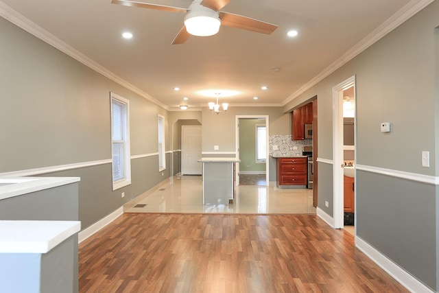 kitchen featuring hardwood / wood-style floors, ceiling fan with notable chandelier, crown molding, and appliances with stainless steel finishes