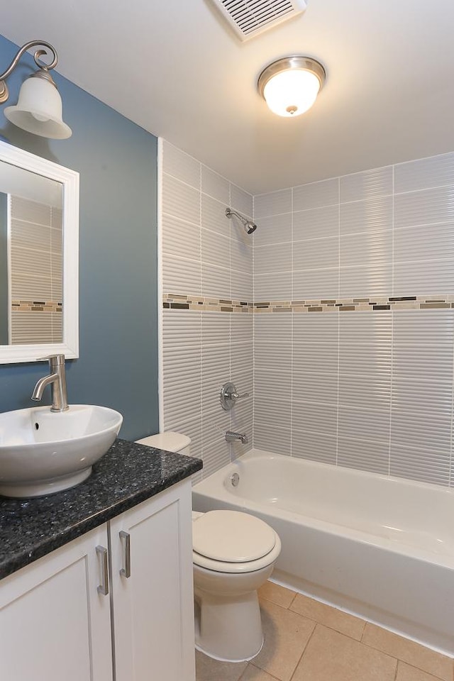 full bathroom featuring tile patterned flooring, tiled shower / bath combo, toilet, and vanity