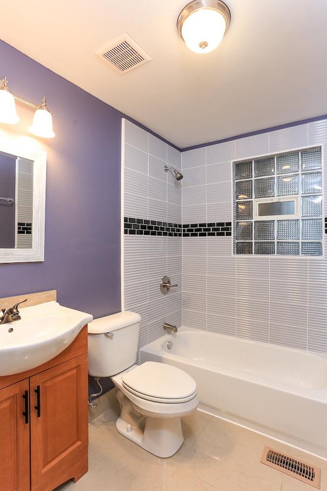 full bathroom with tiled shower / bath, vanity, and toilet