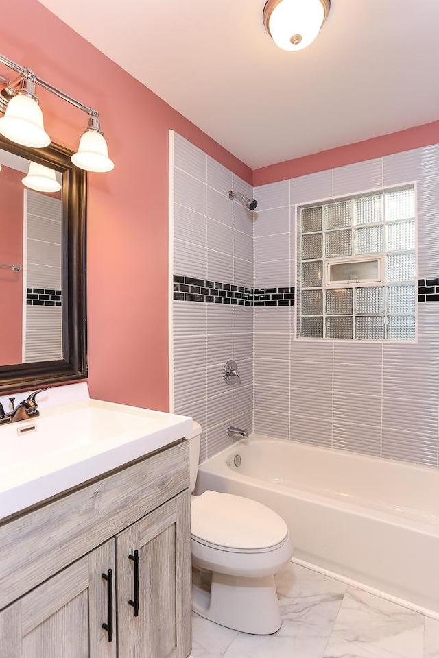 full bathroom featuring tiled shower / bath combo, toilet, and vanity