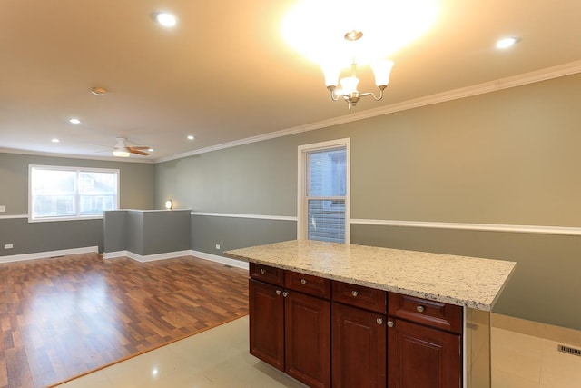 kitchen with light stone countertops, hanging light fixtures, light hardwood / wood-style flooring, crown molding, and ceiling fan with notable chandelier