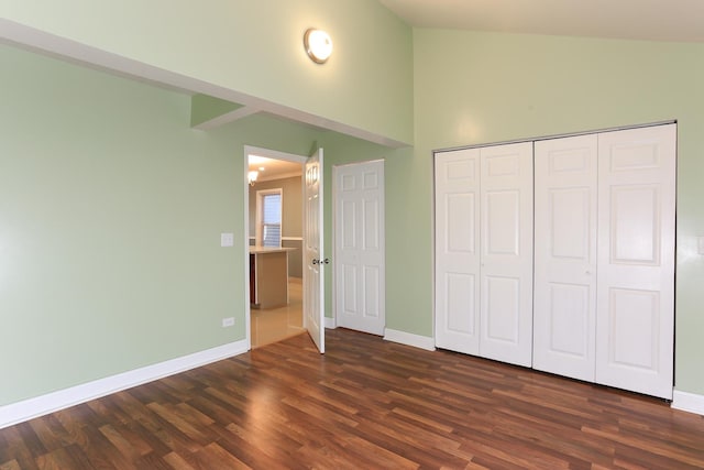 unfurnished bedroom with a chandelier, vaulted ceiling, dark hardwood / wood-style flooring, and a closet