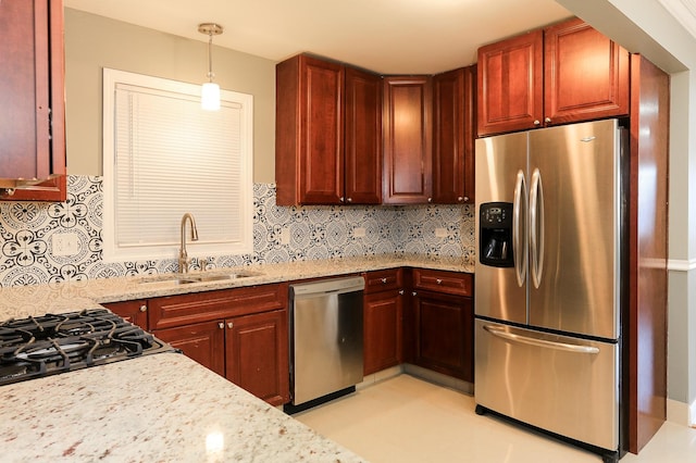 kitchen with sink, light stone countertops, appliances with stainless steel finishes, tasteful backsplash, and decorative light fixtures