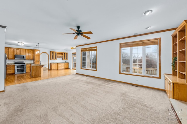 unfurnished living room with ceiling fan, ornamental molding, and light carpet